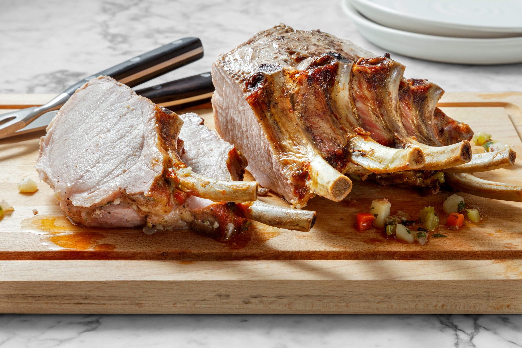 Table view shot of remove foil from rib ends; Slice roast; wooden board; plates; marble surface.