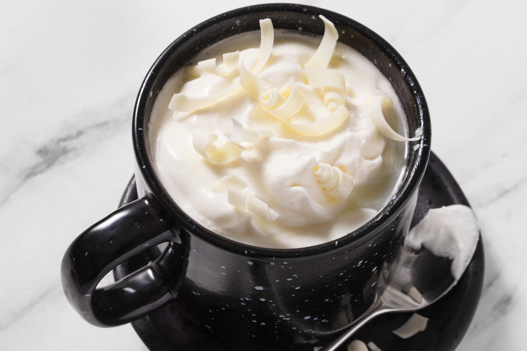 3/4th shot of white hot chocolate topped with whipped cream and white chocolates curls