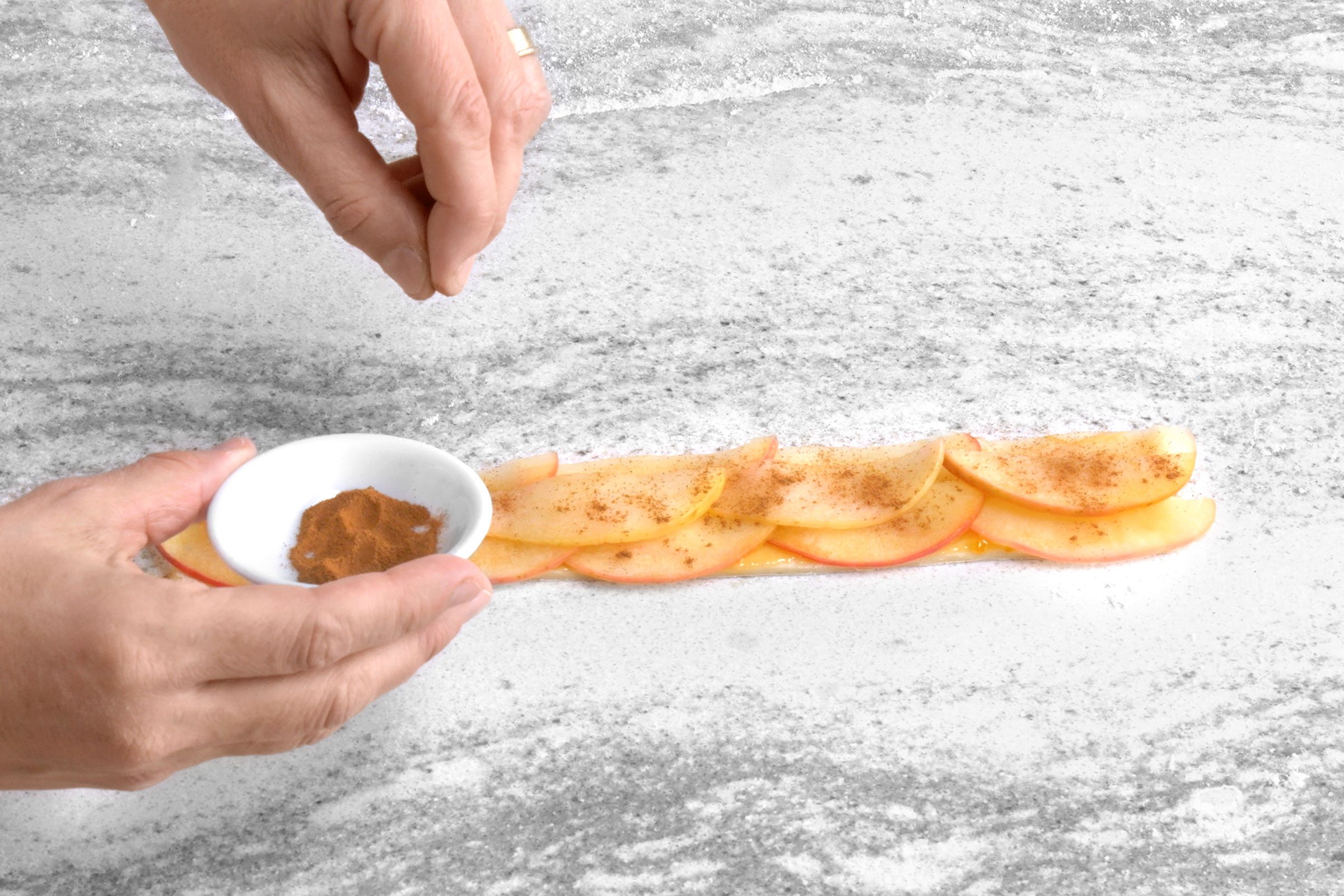 Sprinkling apple overlapping apple slices with cinammon