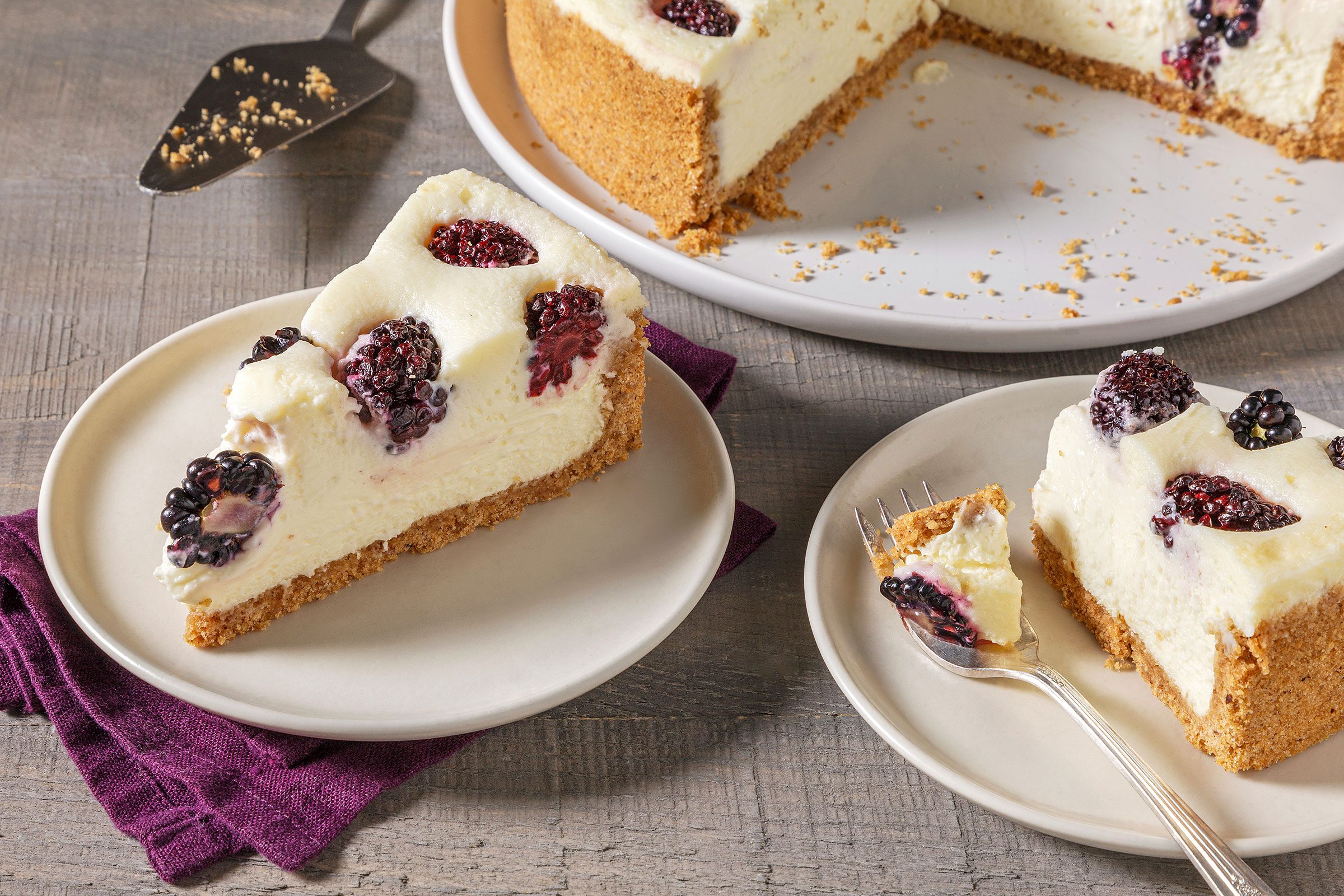 Blackberry Cheesecake sliced into pieces and served on small plates 
