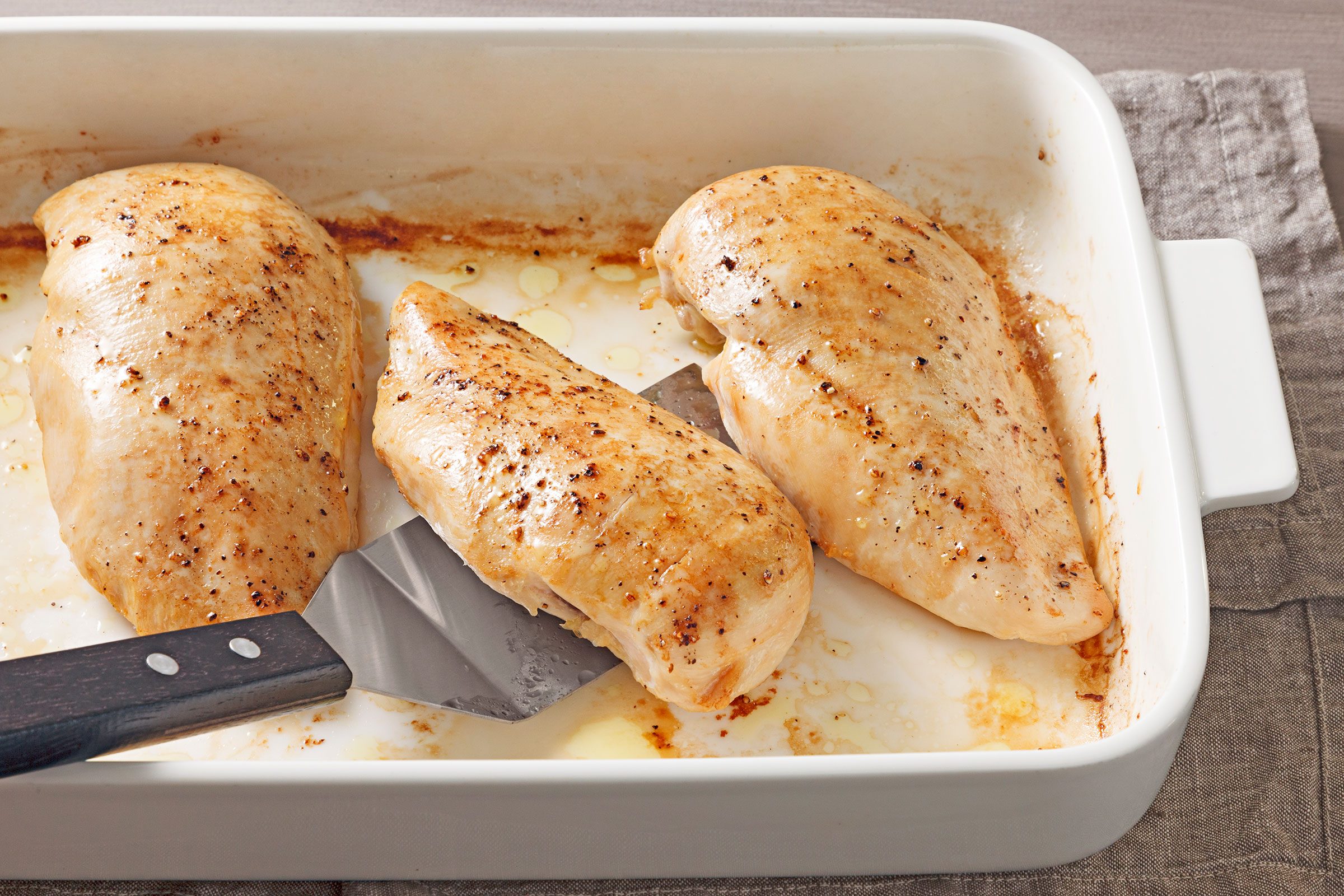 Seasoned Chicken Breasts baked in oven in a greased sheet pan