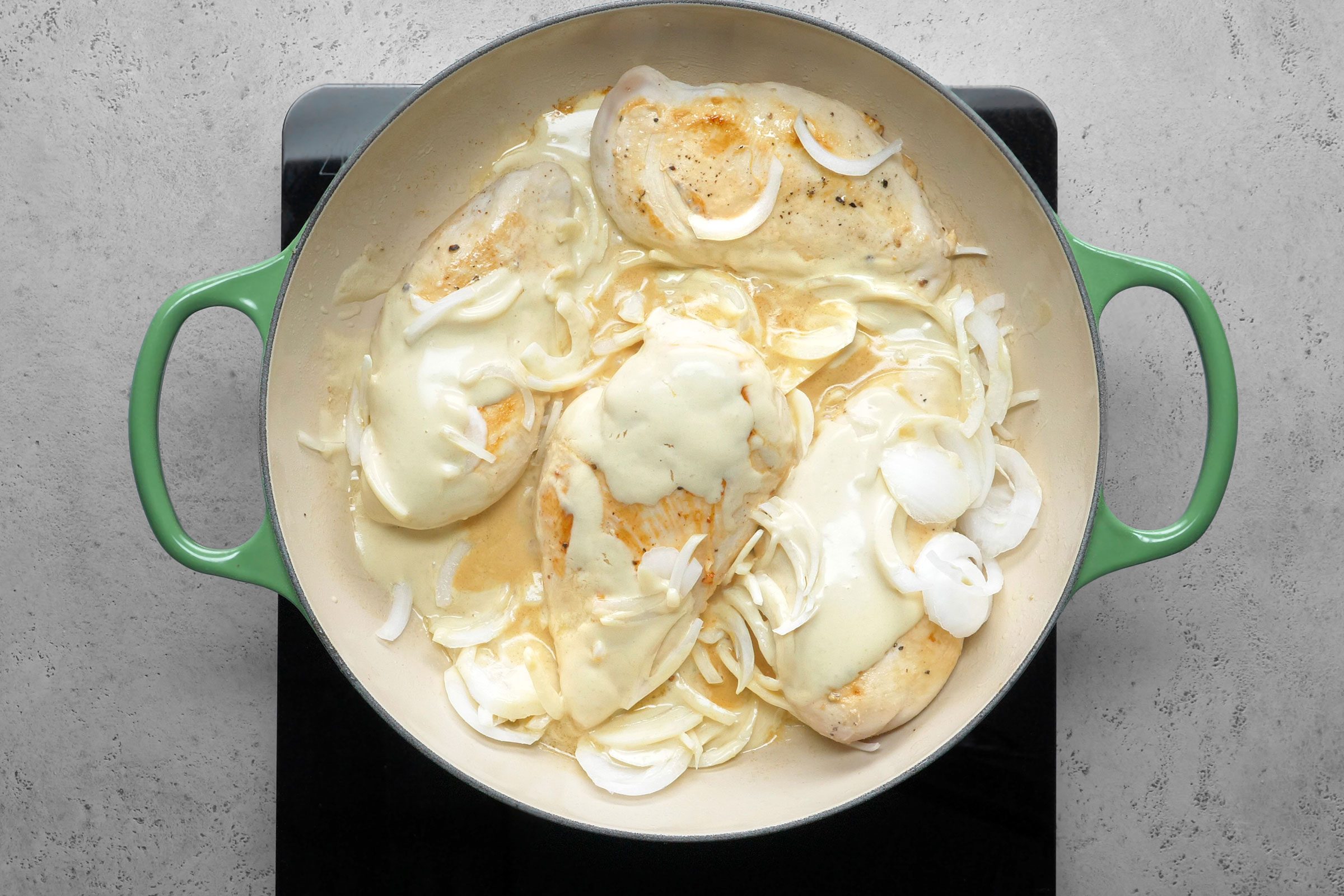 Half and half cream mixture and onions added to roasting chicken breasts in a large skillet