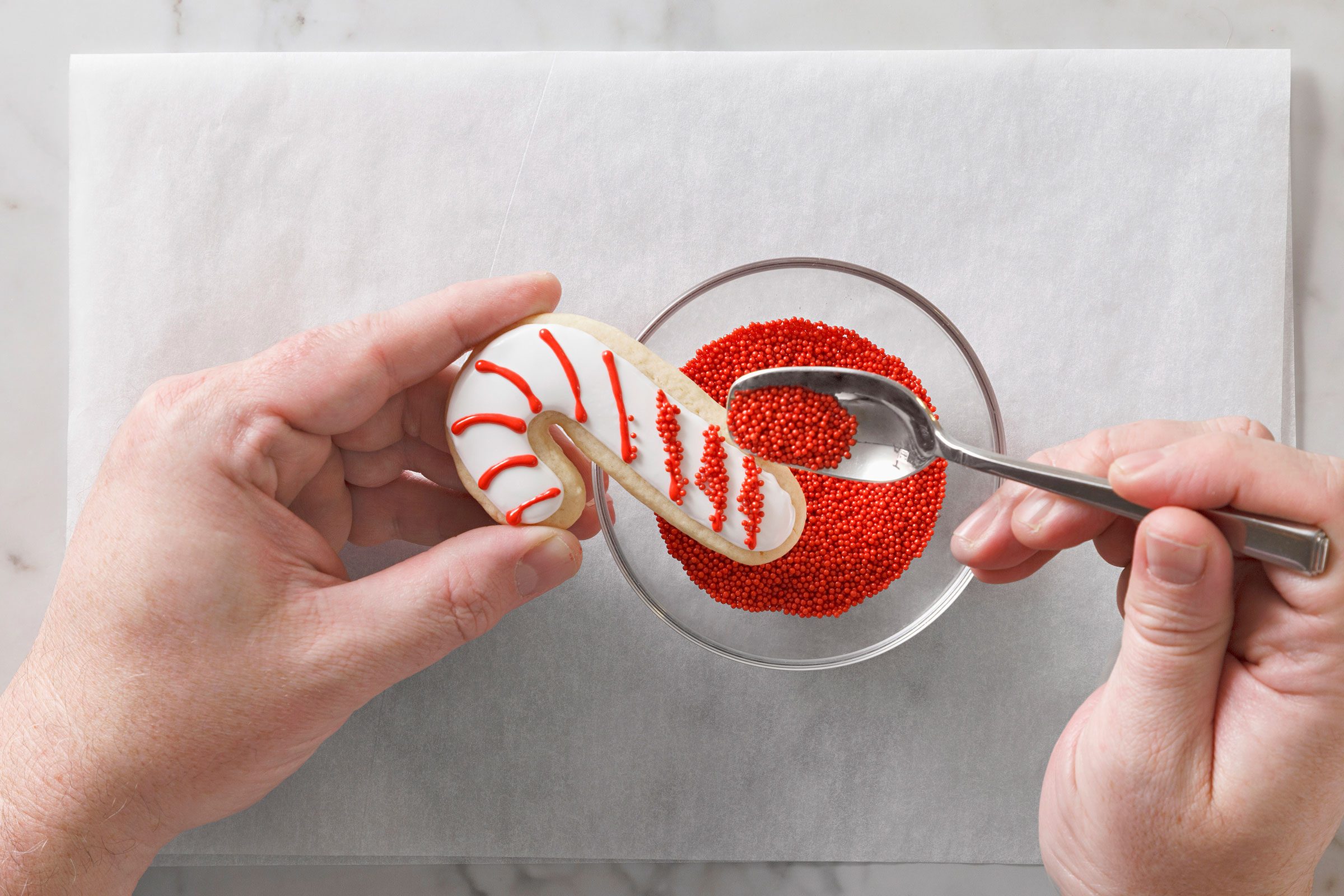 Christmas Cutout Cookies being decorated with red sprinkles candy