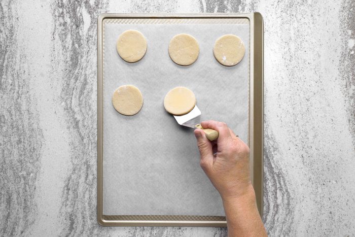 Cookie dough cut into round circles placed on parchment paper lined baking sheet