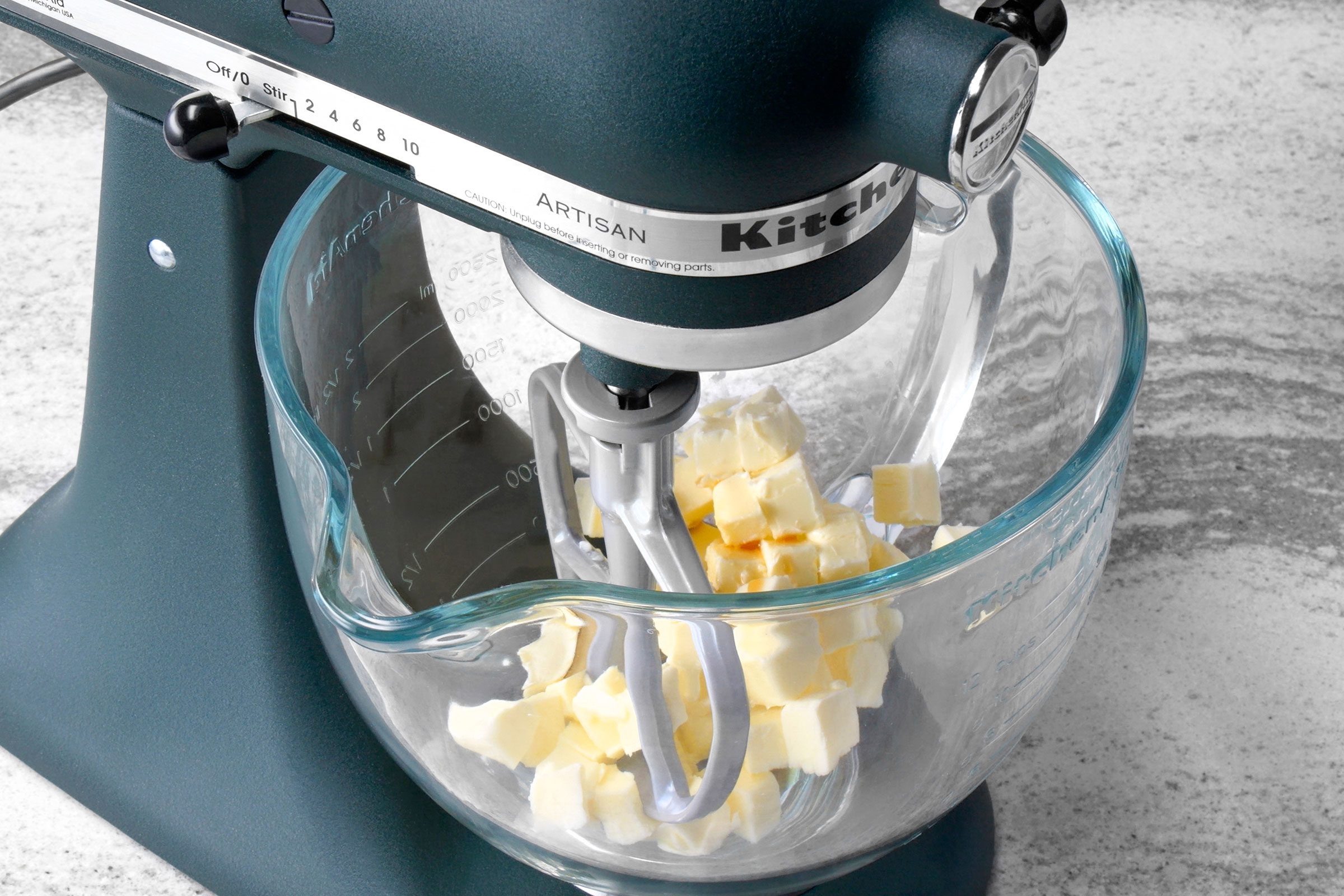 Butter cubes in a large glass bowl with mixer paddle in it