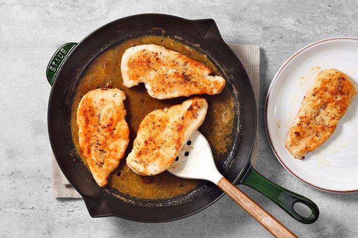 Cooking chicken breasts in chicken broth, lemon zest and seasonings mixture