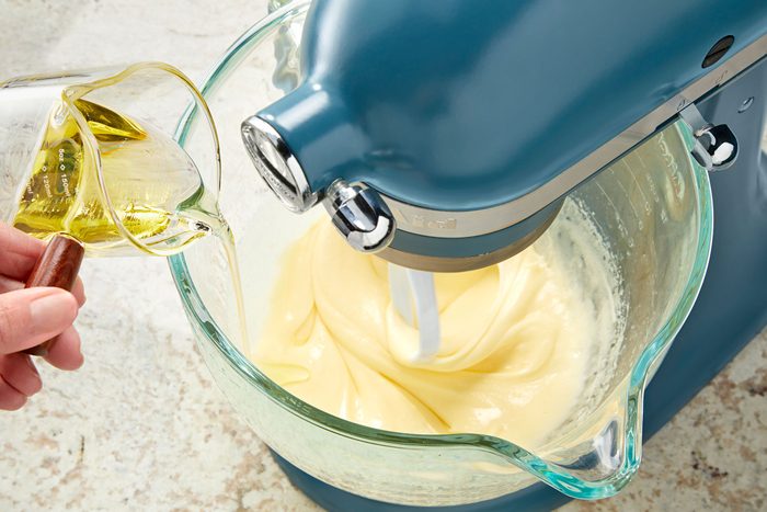 Adding olive oil to the beaten eggs and sugar mixture