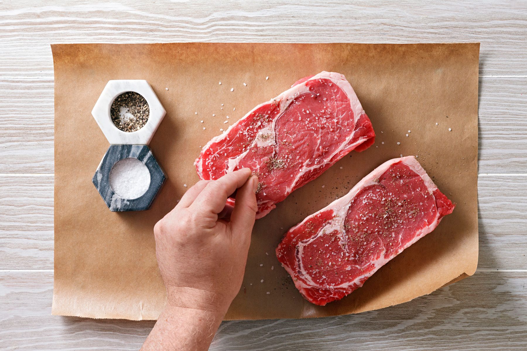 seasoning steaks with salt and pepper