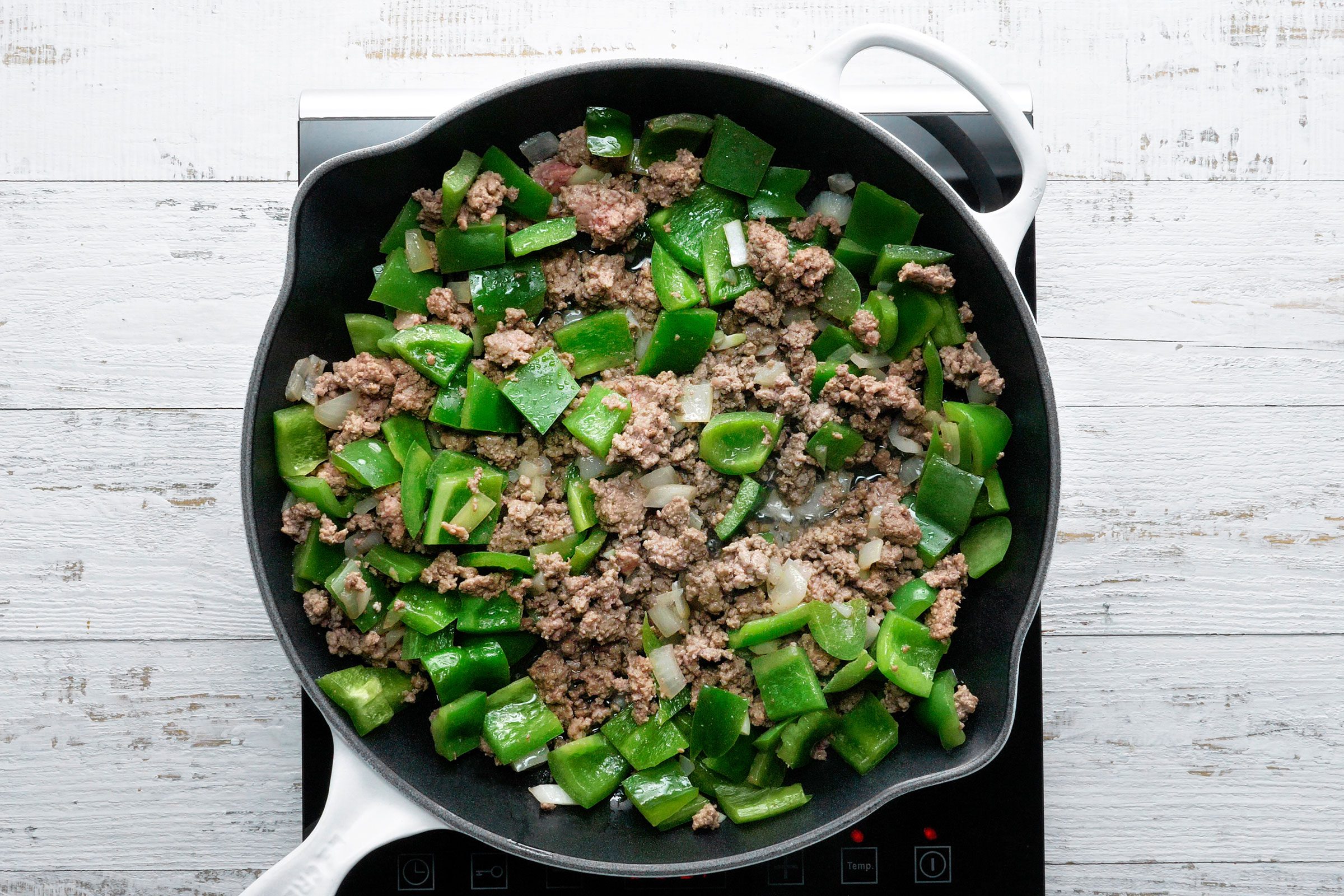 Beef, green peppers and onions cooked together in a large cast iron skillet