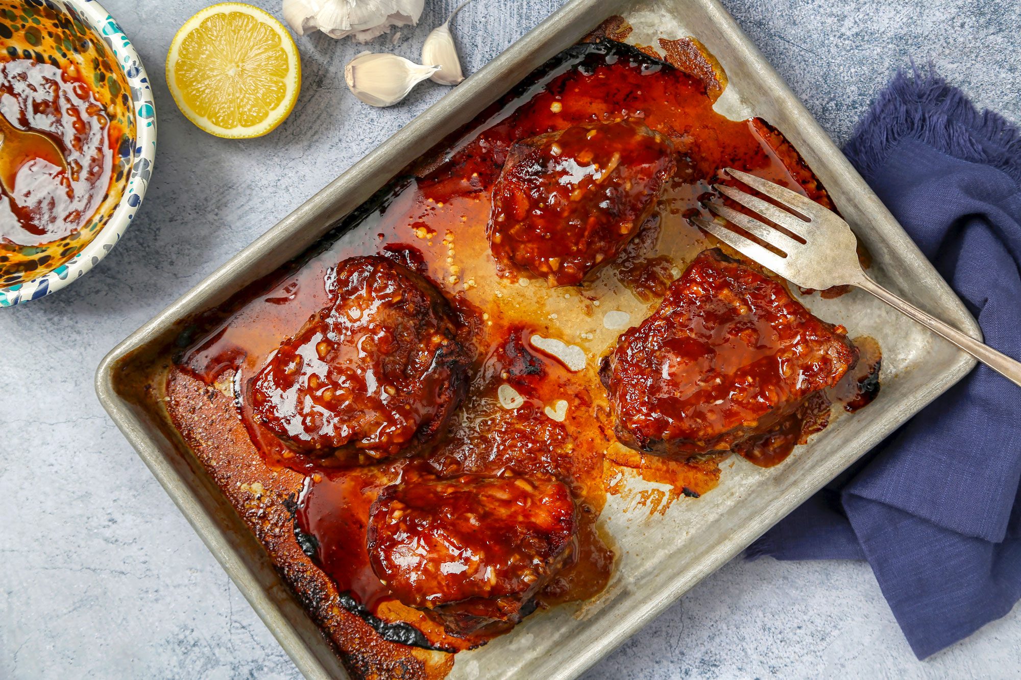 Steak broiled with sauce on a baking sheet.