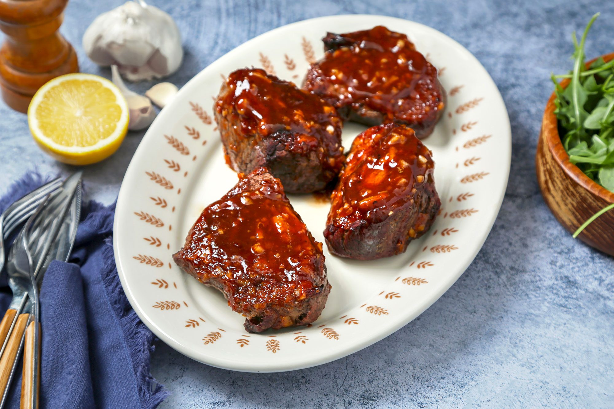 Beef Tournedos on a blue marble surface. Steak with sauce on a serving platter.