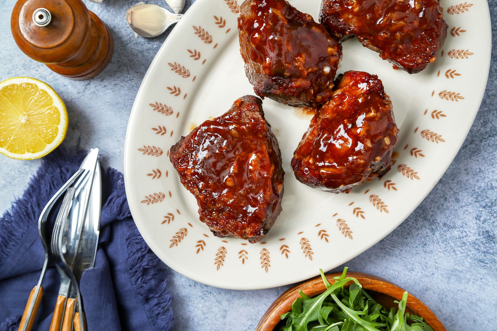 Beef Tournedos on a blue marble surface. Steak with sauce on a serving platter.