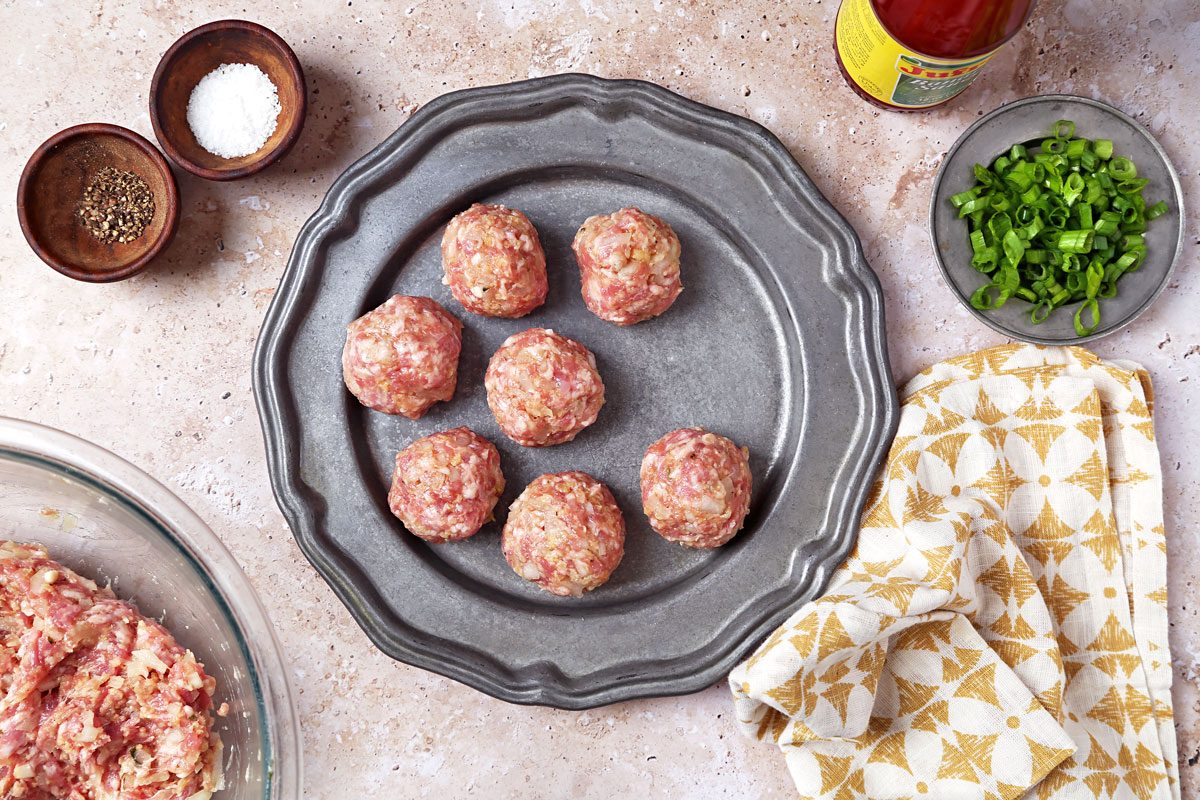 Meatballs formed on a silver plate.
