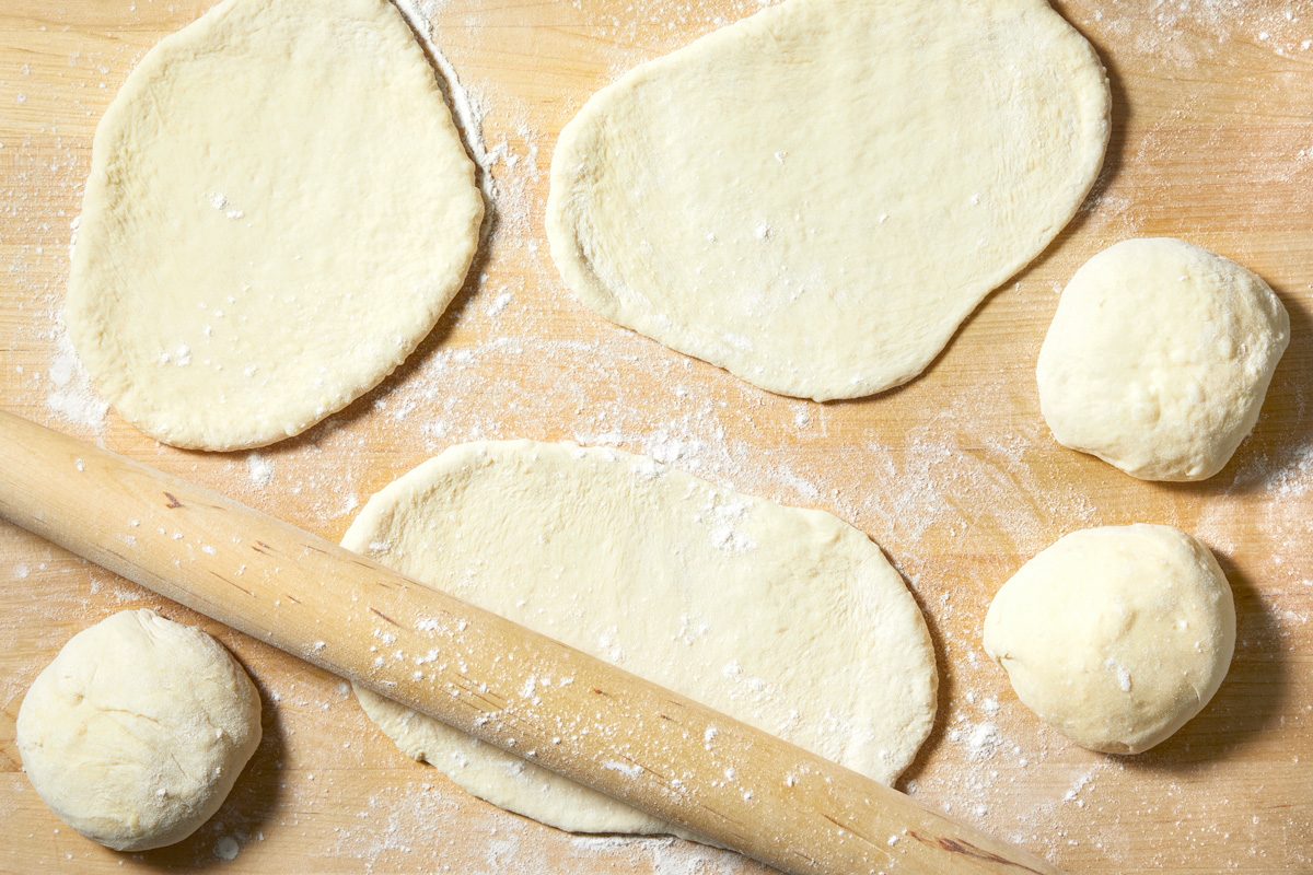 ball shaped dough being rolled into ovals