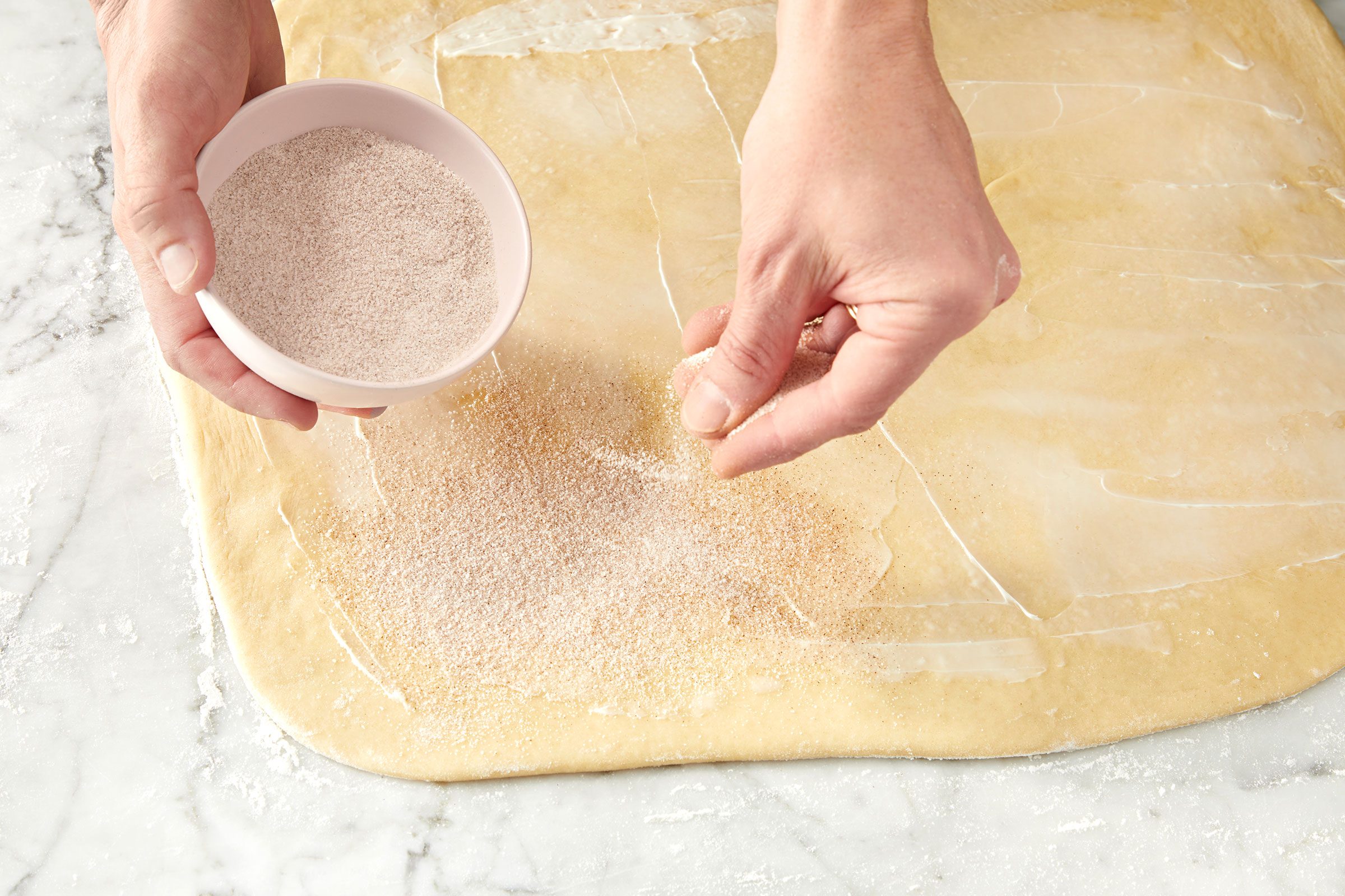 Sugar and cinnamon sprinkled over the rectangular shaped dough sheet