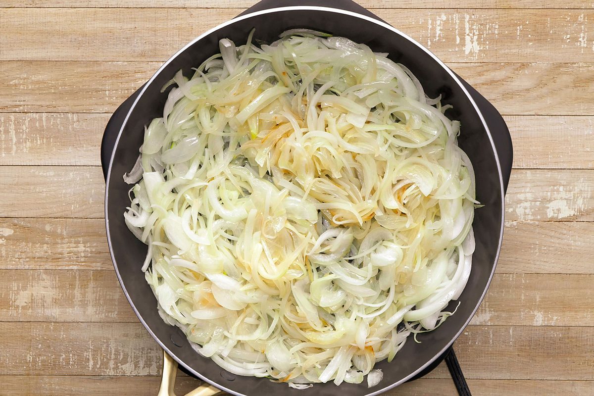 sliced onions being cooked in a skillet