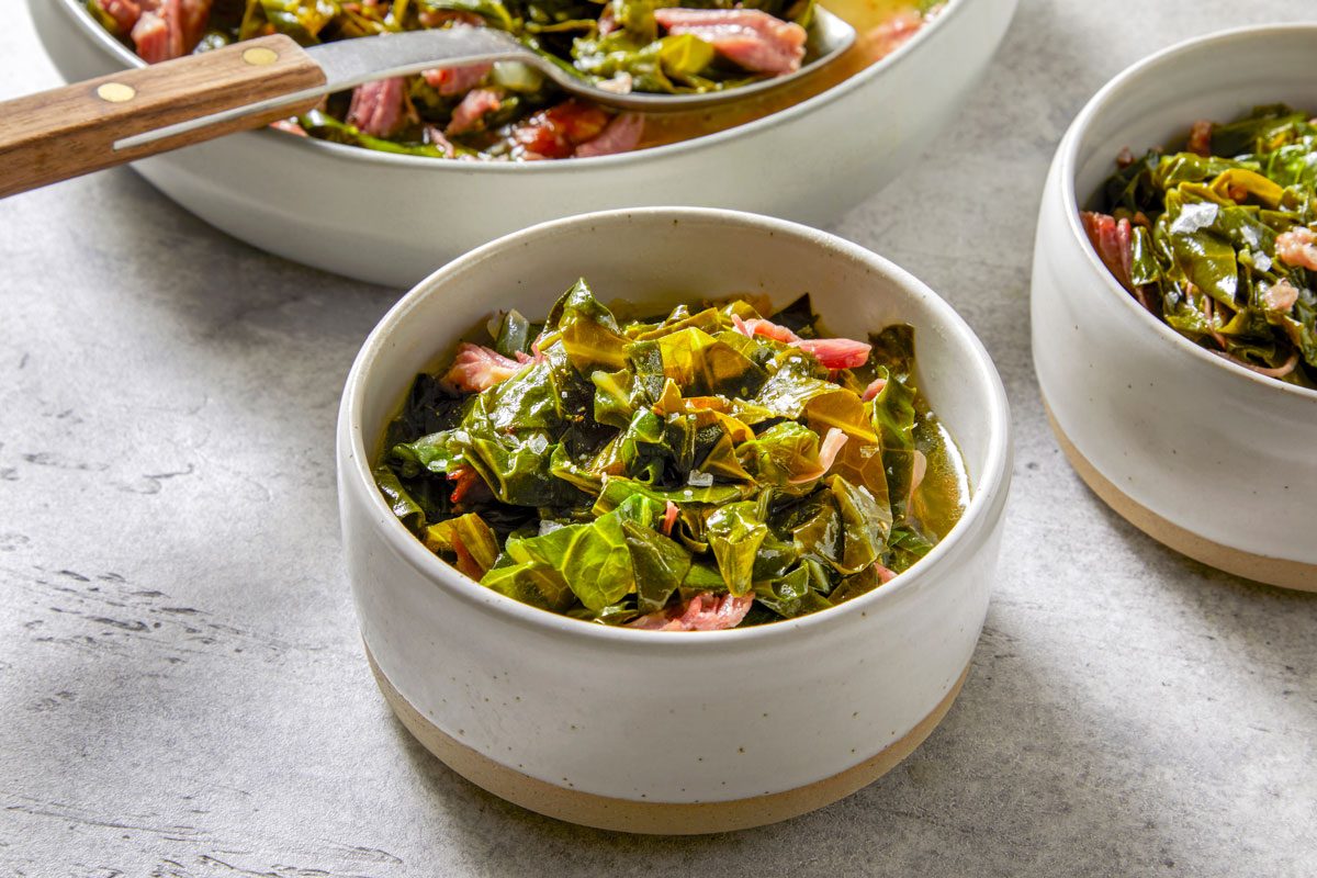 Close shot of Collard Greens with Smoked Turkey; in a large bowl; served in two bowls; serving spoon; marble surface