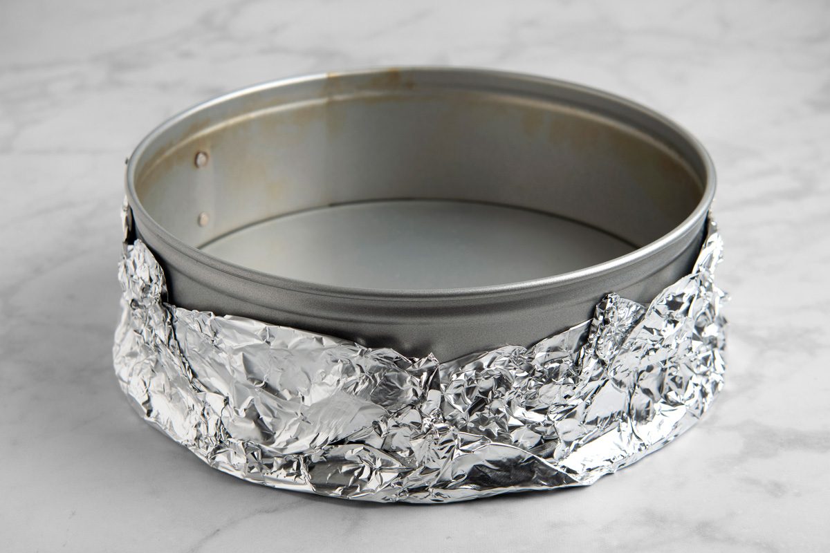Bottom half of a 9-inch springform pan wrapped with three layers of aluminium foil.