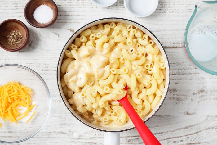White pot filled with macaroni and cheese; the pasta is cooked and coated in a creamy sauce