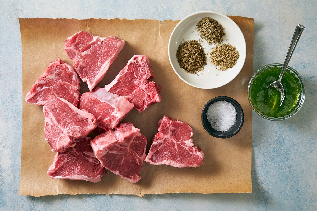 Overhead view of ingredients required to make lamb chops on brown parchment paper.
