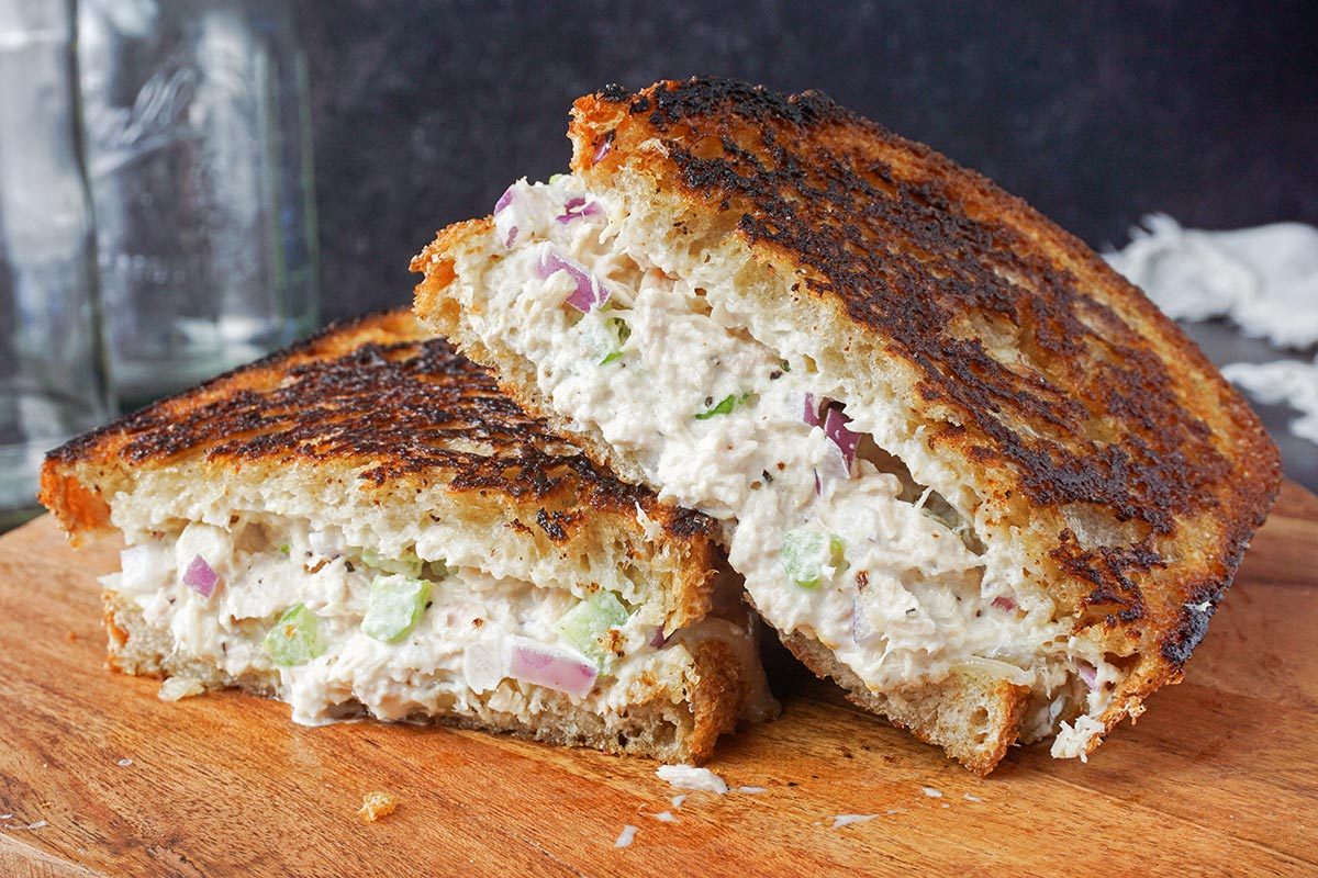 A tuna melt cut in half on a wooden cutting board