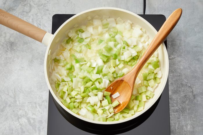 Overhead shot of add butter; cook onion and celery until crisp-tender 3-5 minutes; woodens poon; marble surface