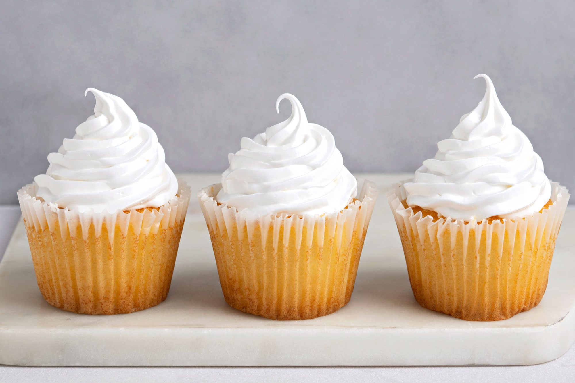 Table view shot of Fluffy White Frosting; served on cupcakes; marble surface;