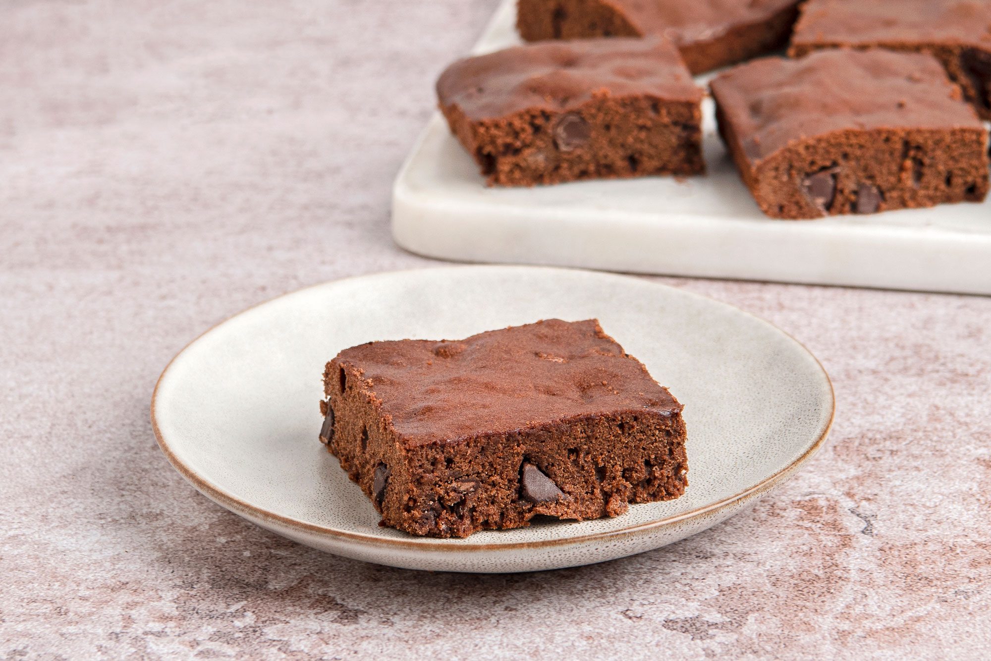 Close shot of Easy Gluten Free Brownies; place on white tray; served on a small plate; light brown marble surface
