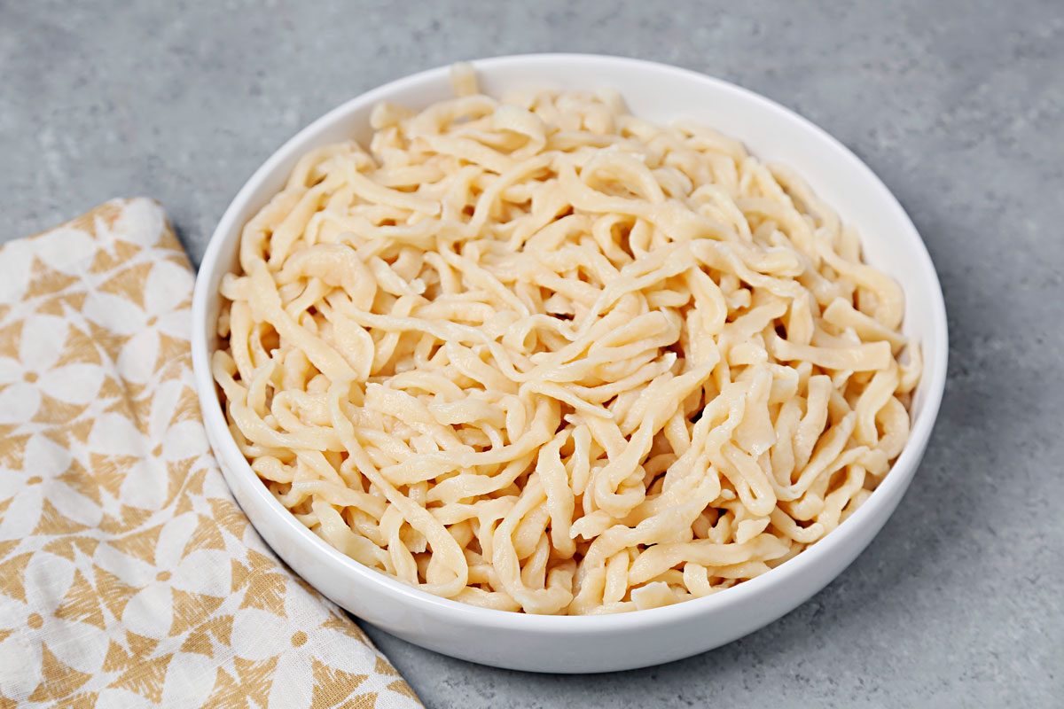 Boiled udon noodles in a large white serving bowl; 3/4th