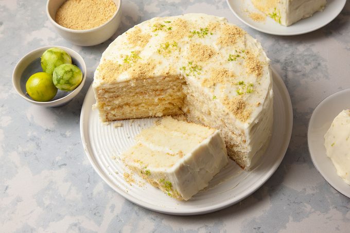 Key Lime Cake on a white plate with a big chunk cut