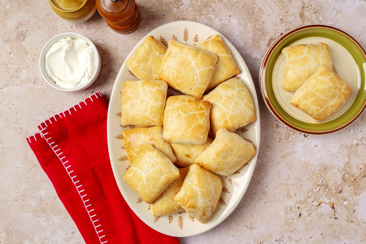 Knish served on a plate with sour cream