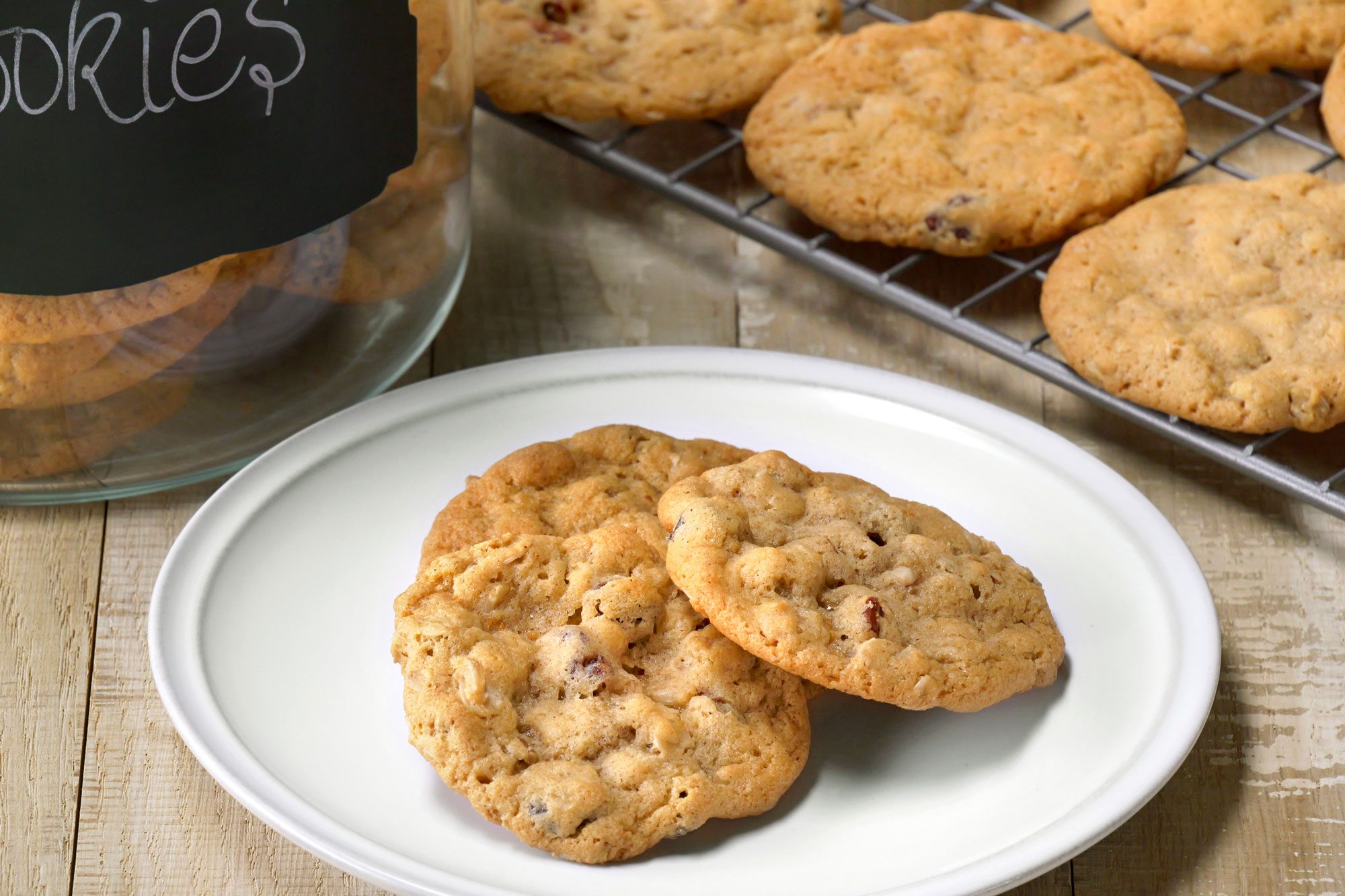 Table view shot of Oatmeal Raisin Cookies; remove to a wire rack to cool; serve on plate; store in glass jar; wooden surface;