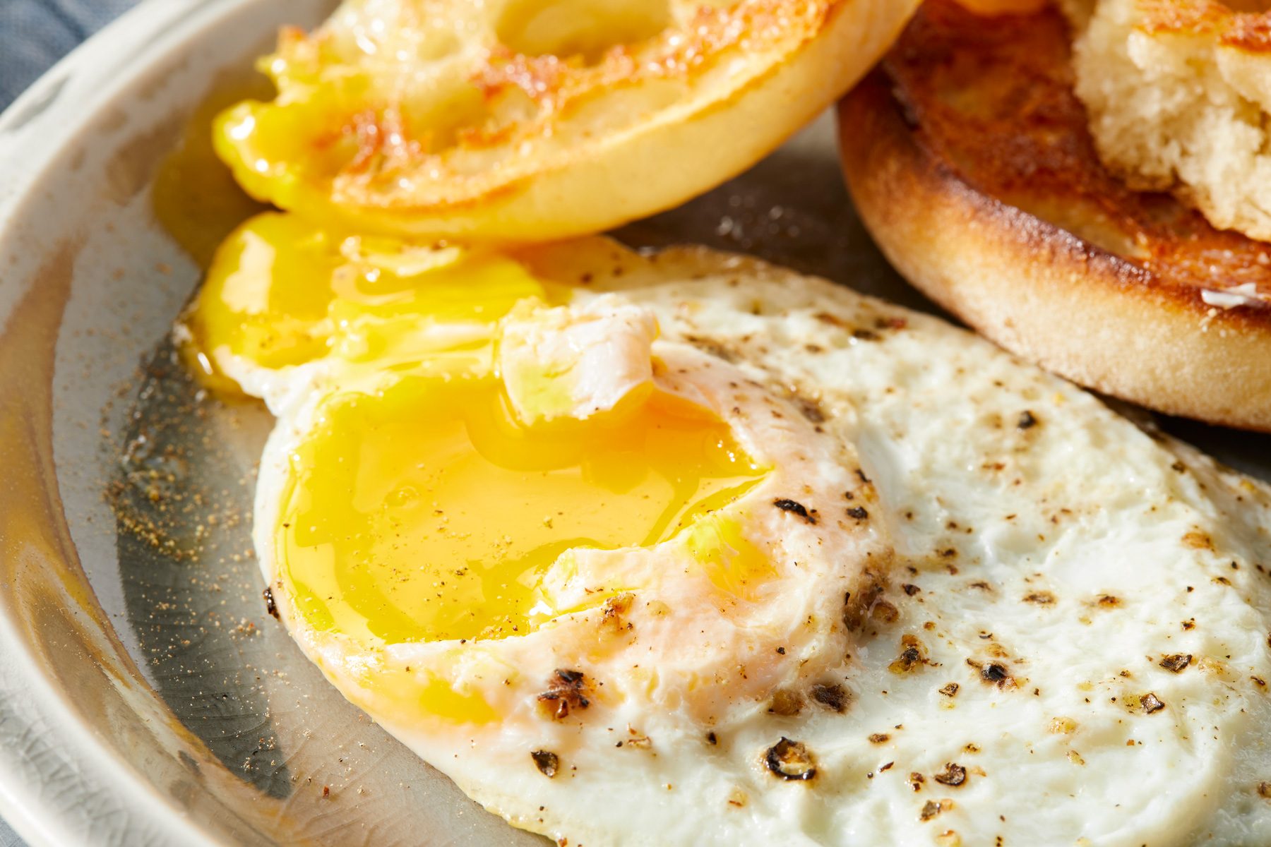 Close up shot of Over-Easy Eggs; serve hot on a plate with bun; blue napkin;