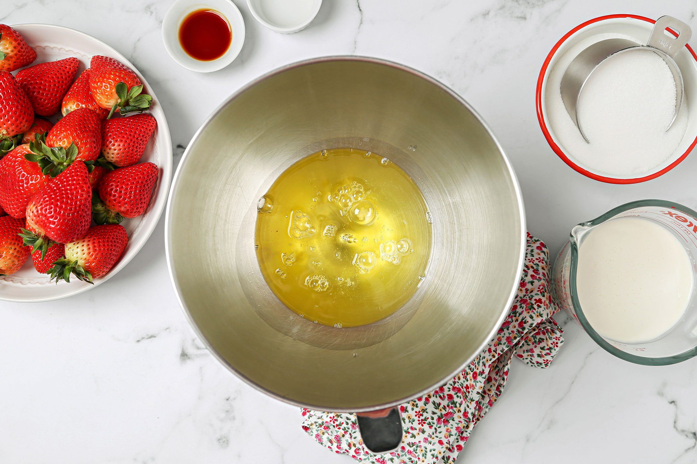 Egg whites in a large bowl with strawberries and milk on side