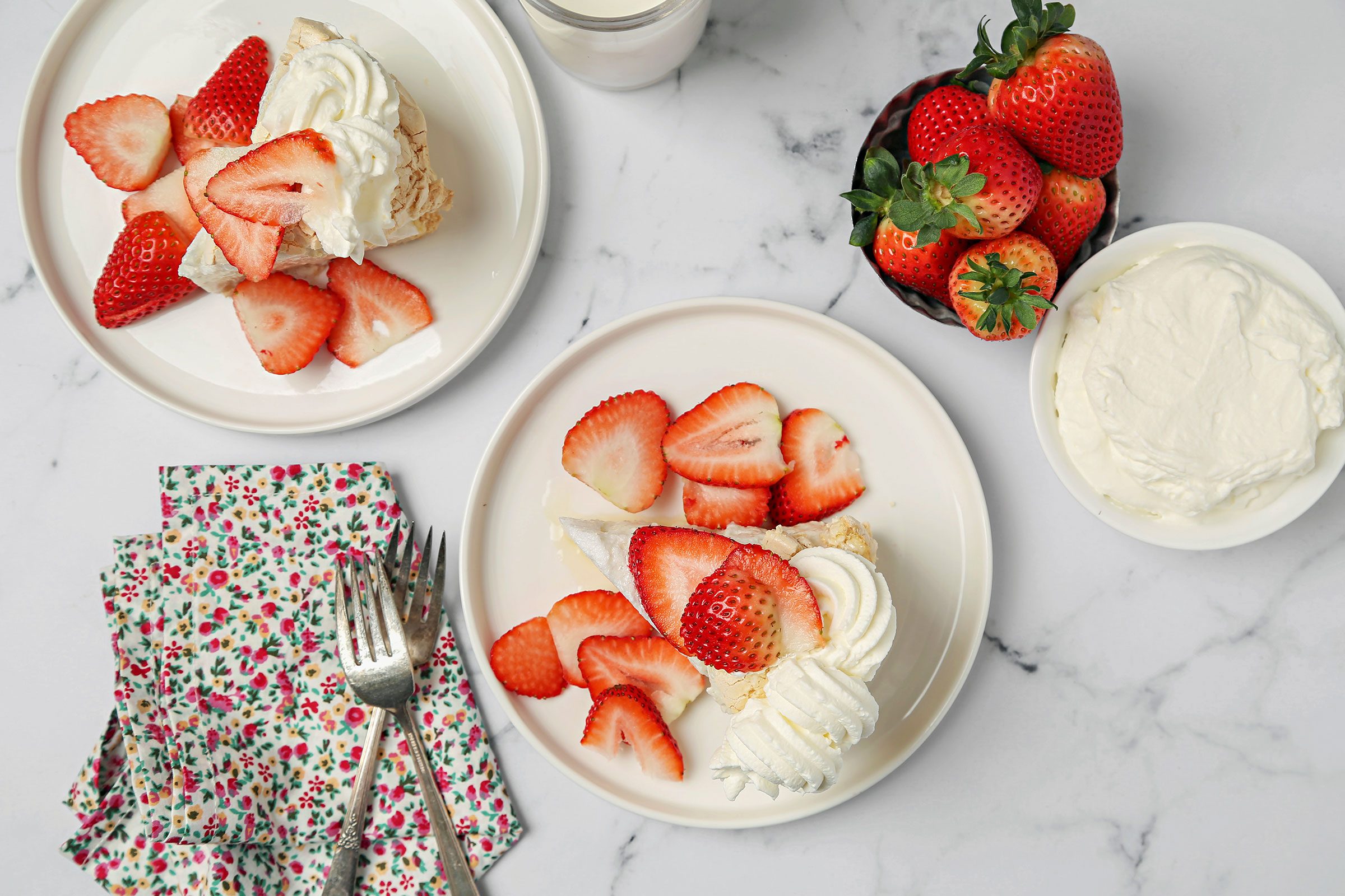 Schaum Torte with dollops of whipped cream and freshly chooped strawberries