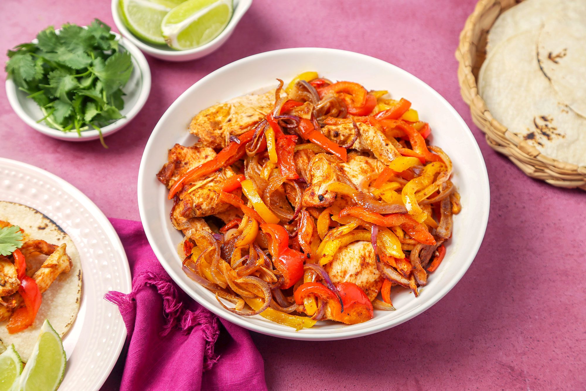 Sheet Pan Chicken Fajitas served on tortillas on a pink plate