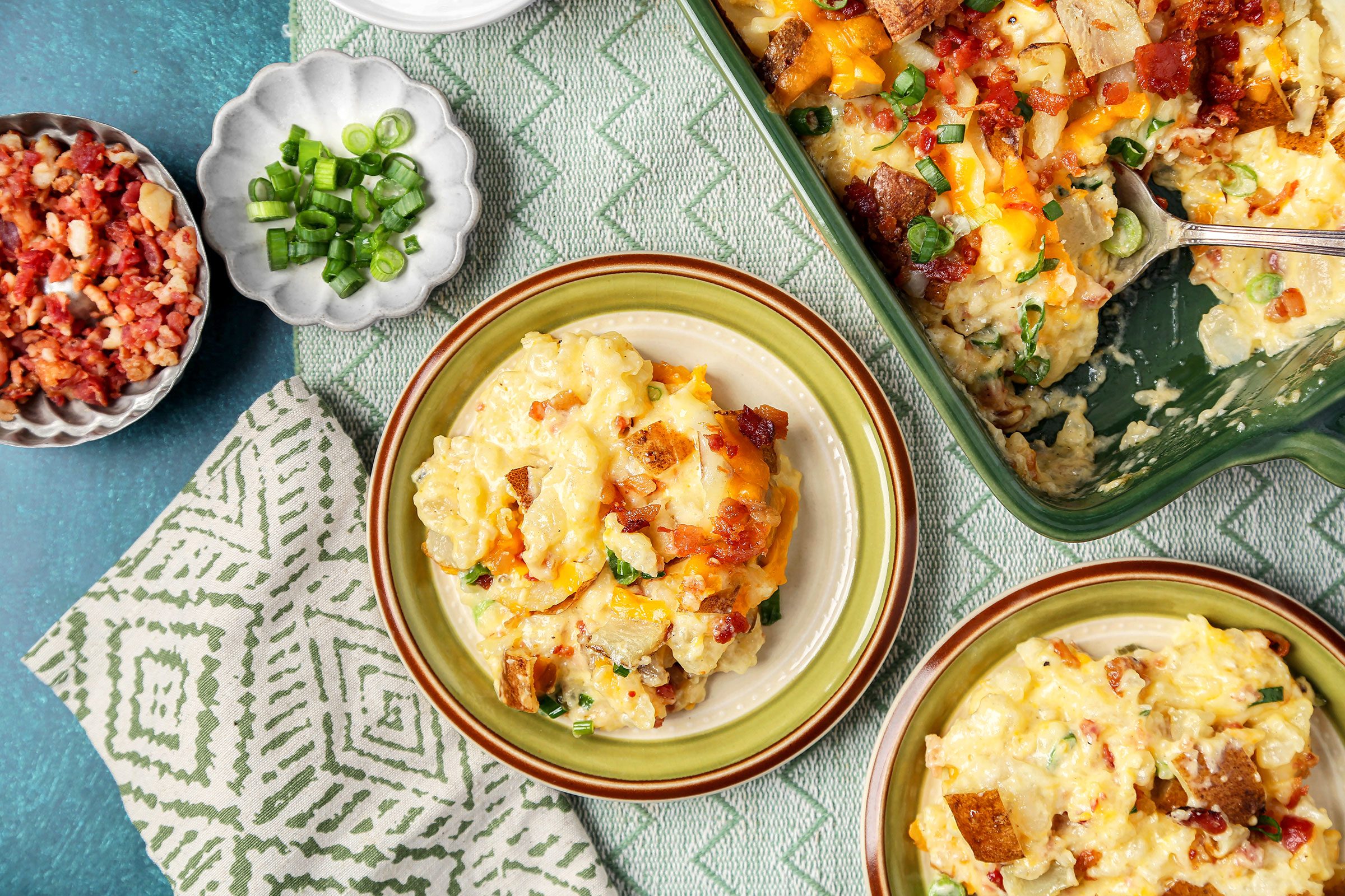 Twice Baked Potato Casserole served in small plates with bacon and onions on side