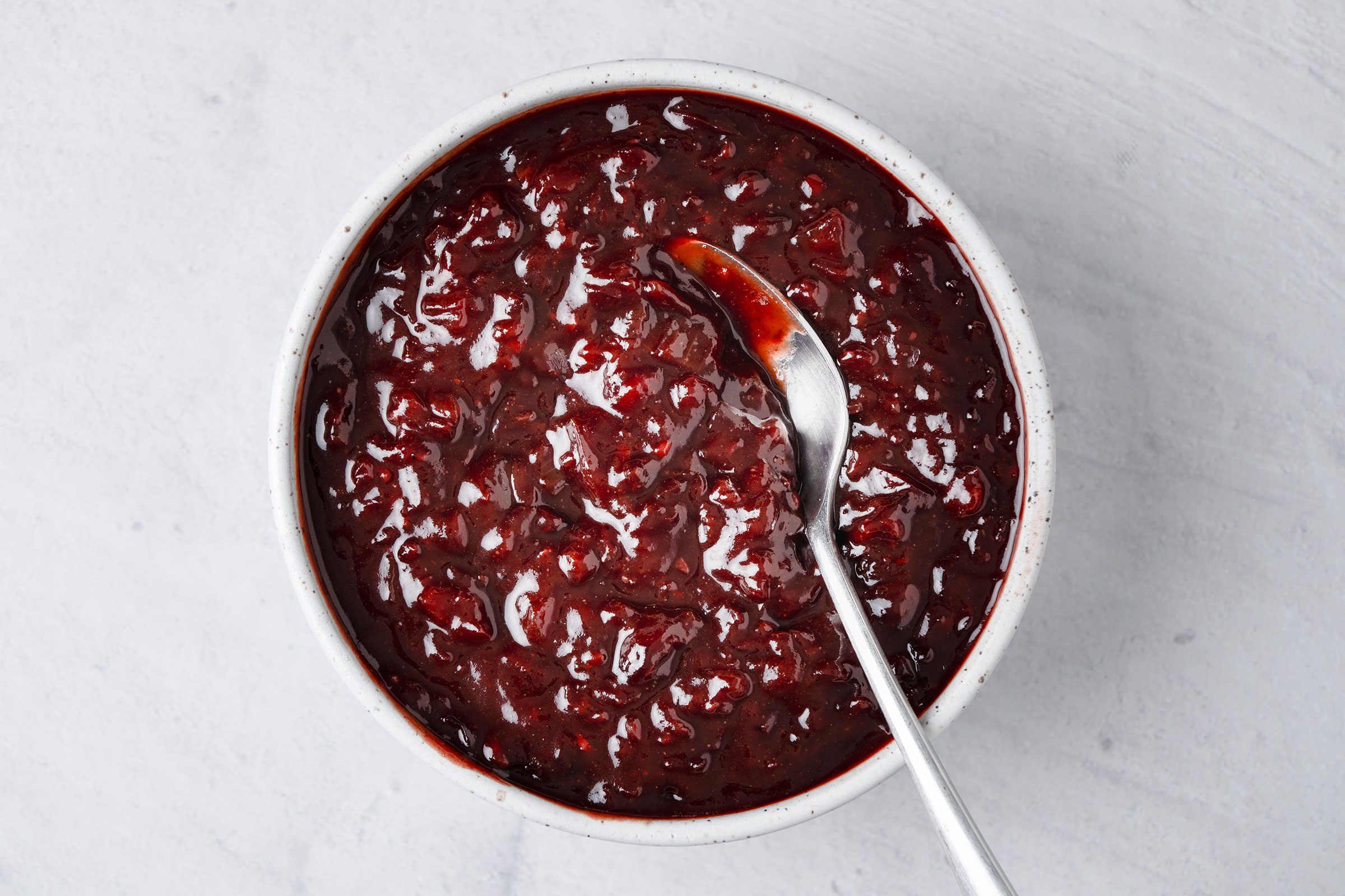 Cherry Barbecue Sauce in a white bowl with a metal spoon in it