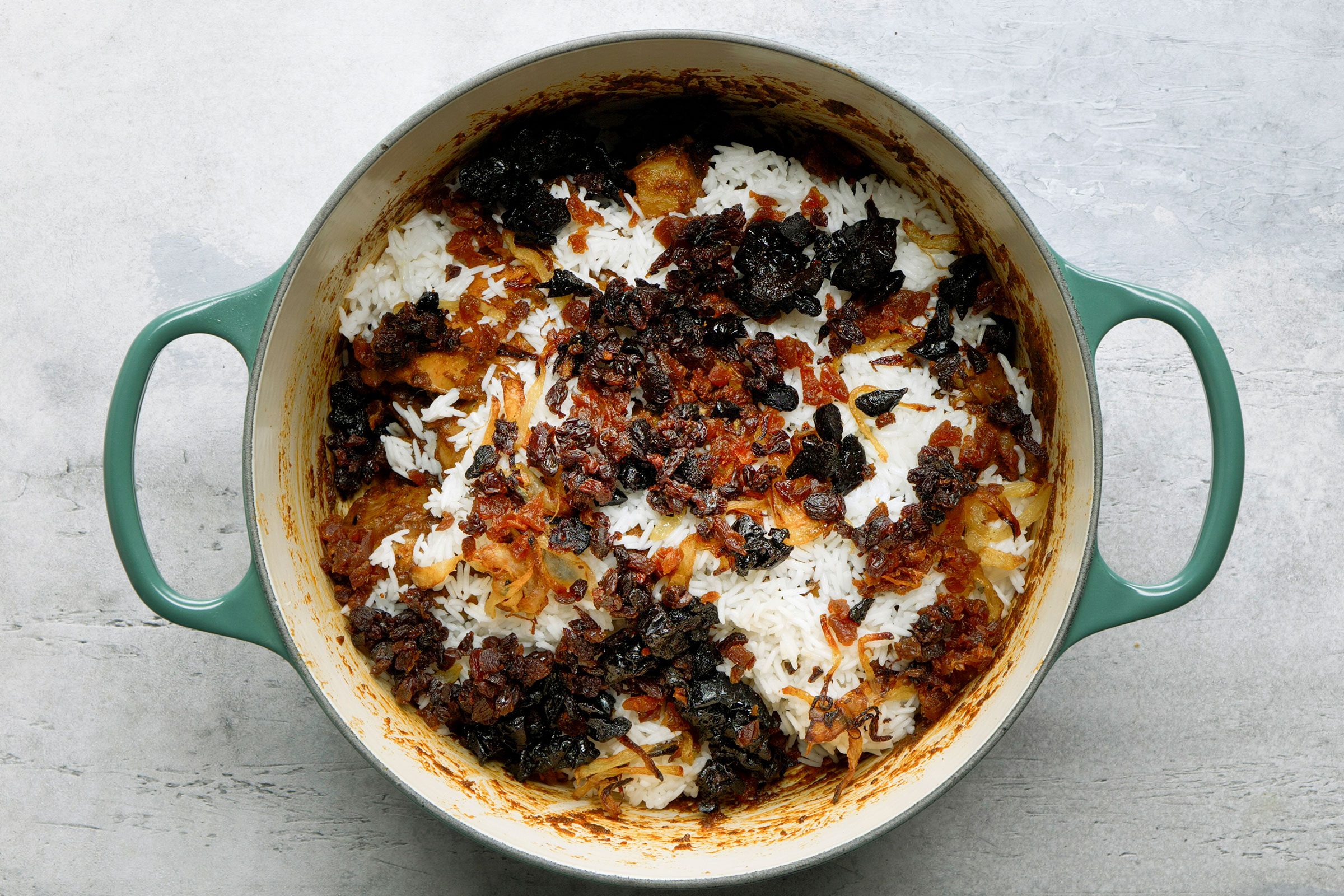 Layers of chicken, rice, fried onions and dry fruits in a dutch oven
