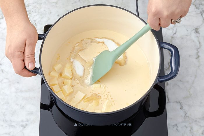 Sugar, milk and butter are being mixed in a large pan