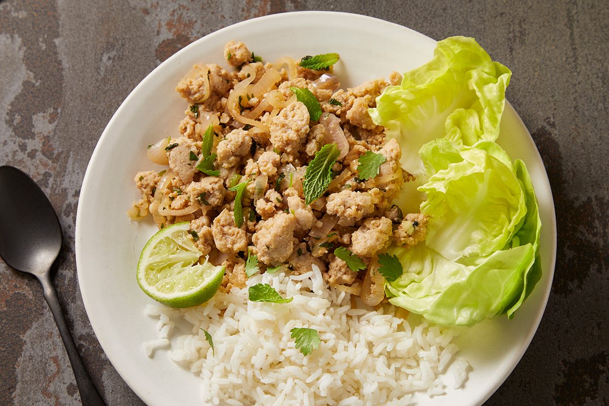 Overhead shot of Larb Gai served with boston lettuce leaves abd hot cooked sticky rice