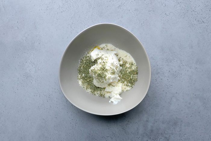 Overhead shot a bowl; mix eggs; ricotta cheese; Parmesan cheese; parsley and pepper; grey surface;