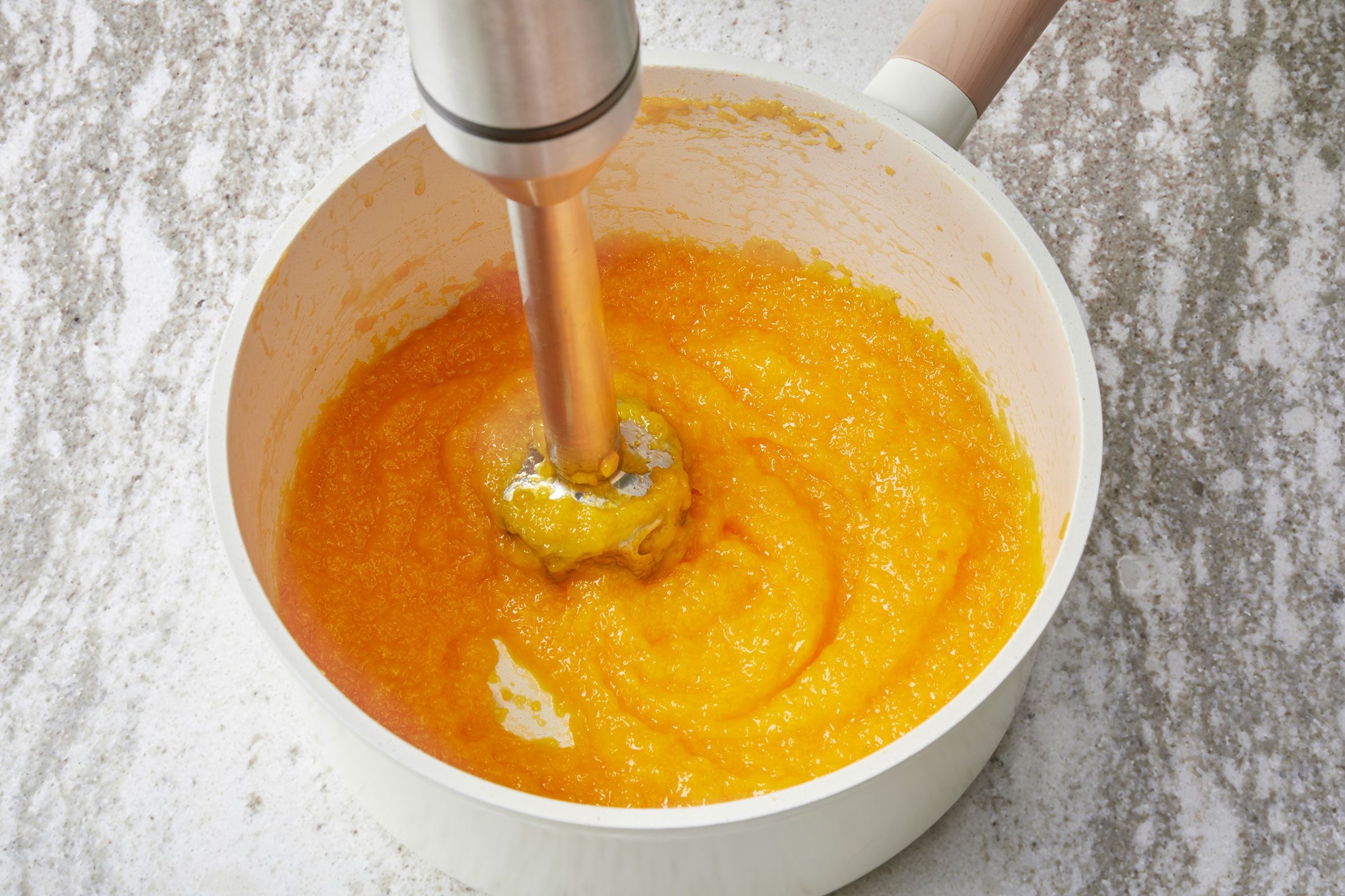 Using an immersion blender to puree the mango mixture