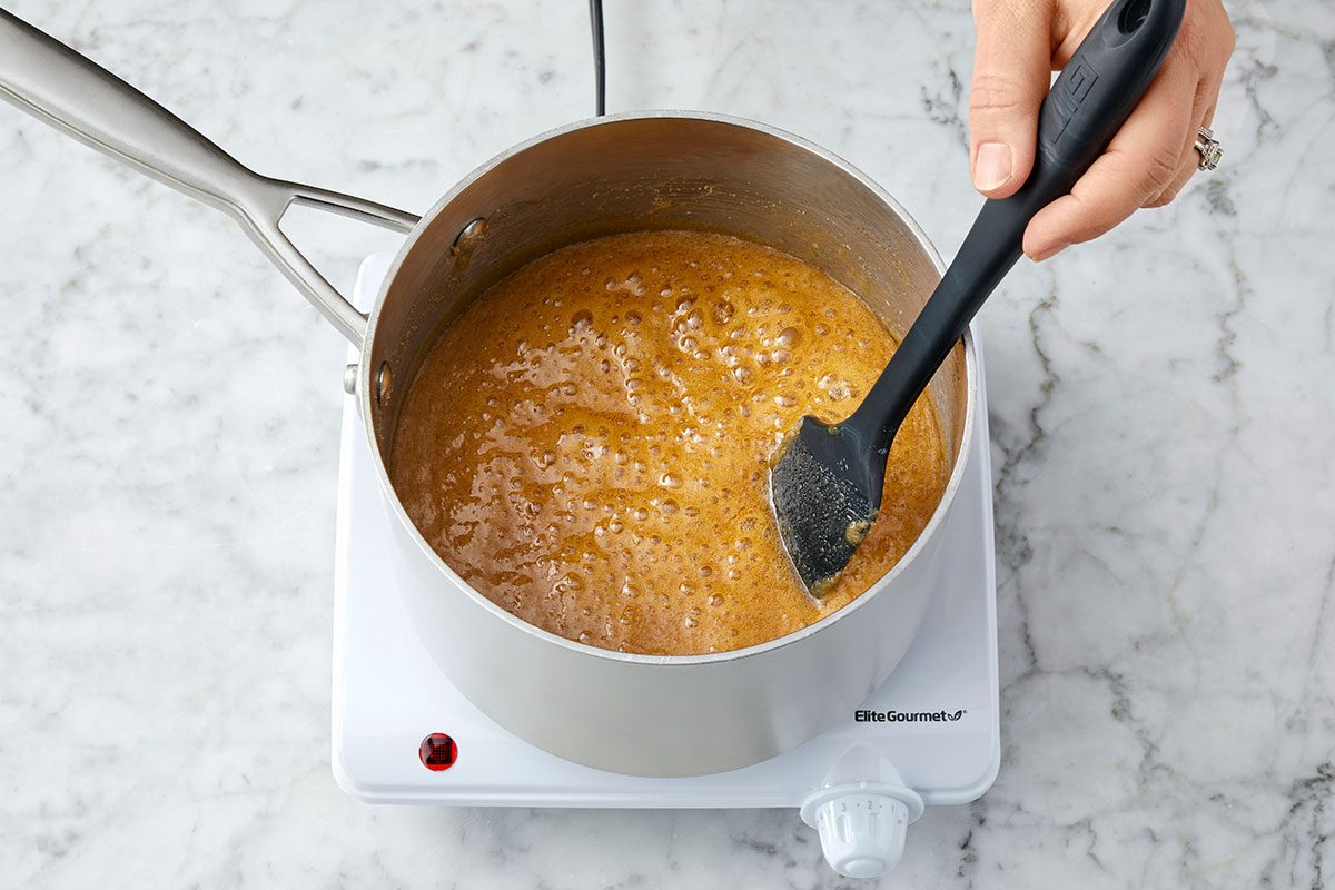Sugar, milk, corn syrup and salt are mixed and boiling in a pan