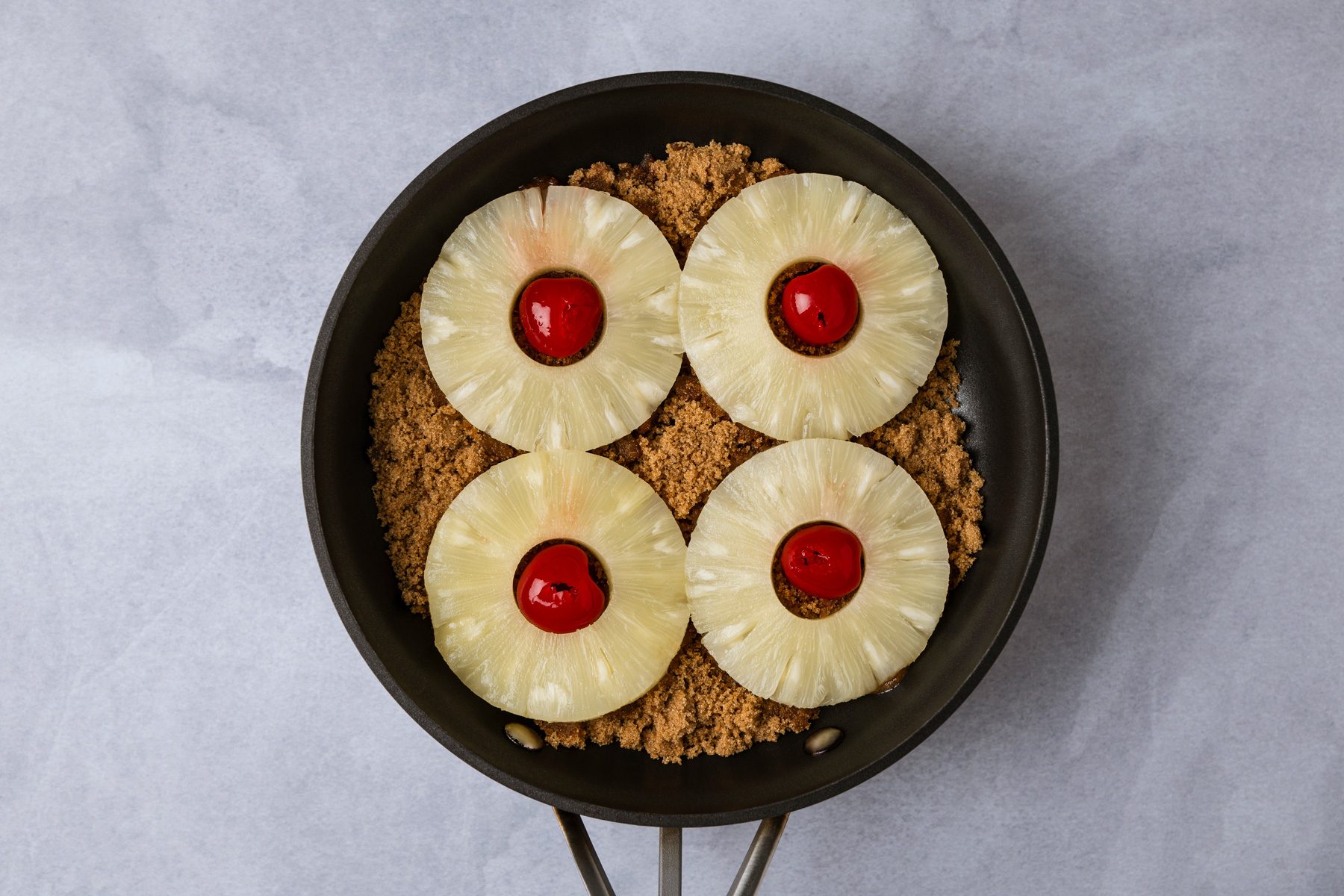 Arrange pineapple in a single layer over brown sugar; place a cherry in the center of each pineapple slice.