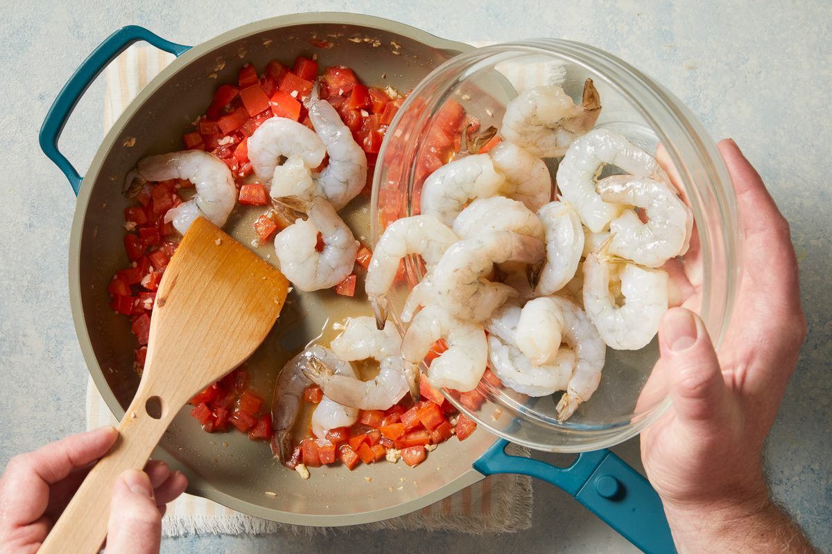 shrimp being added to skillet for cooking