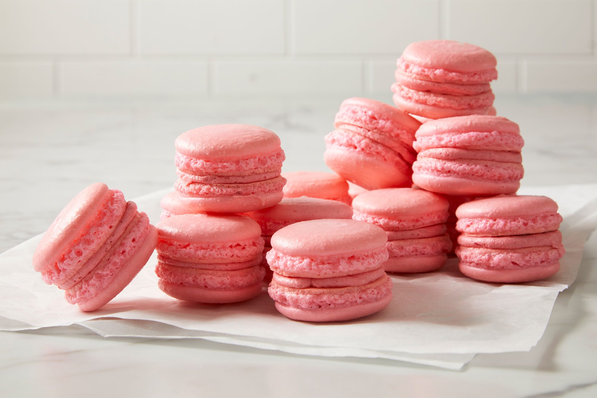 Table view shot of Strawberry Macarons; placed over wax sheet; on marble surface;