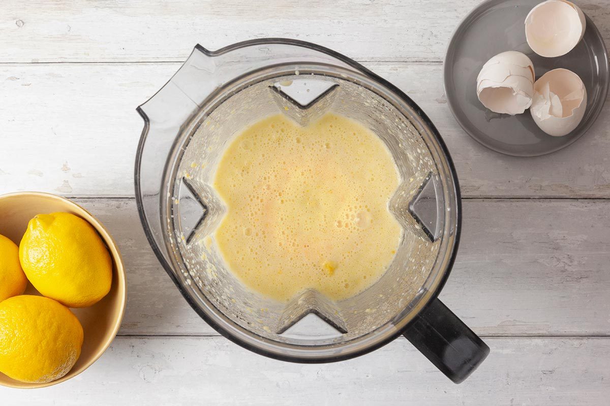 lemon, butter, sugar, eggs and vanilla are being blended in a processor.