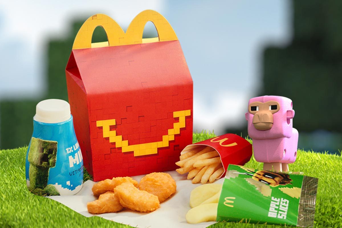 Minecraft themed McDonald's Happy meal box with milk, chicken nuggets, fries, apple slices, and a minecraft pig toy