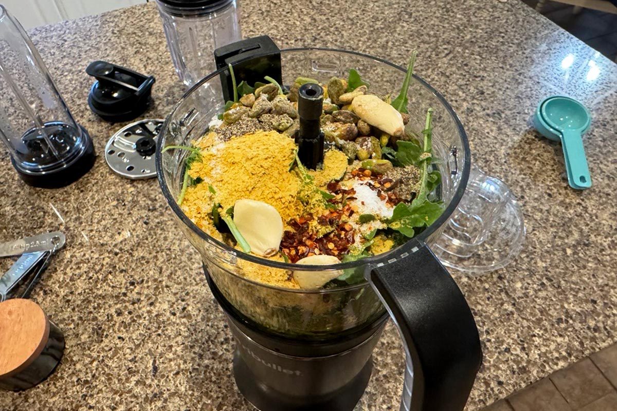 Nutribullet food processer attachment with pesto ingredients on a kitchen counter